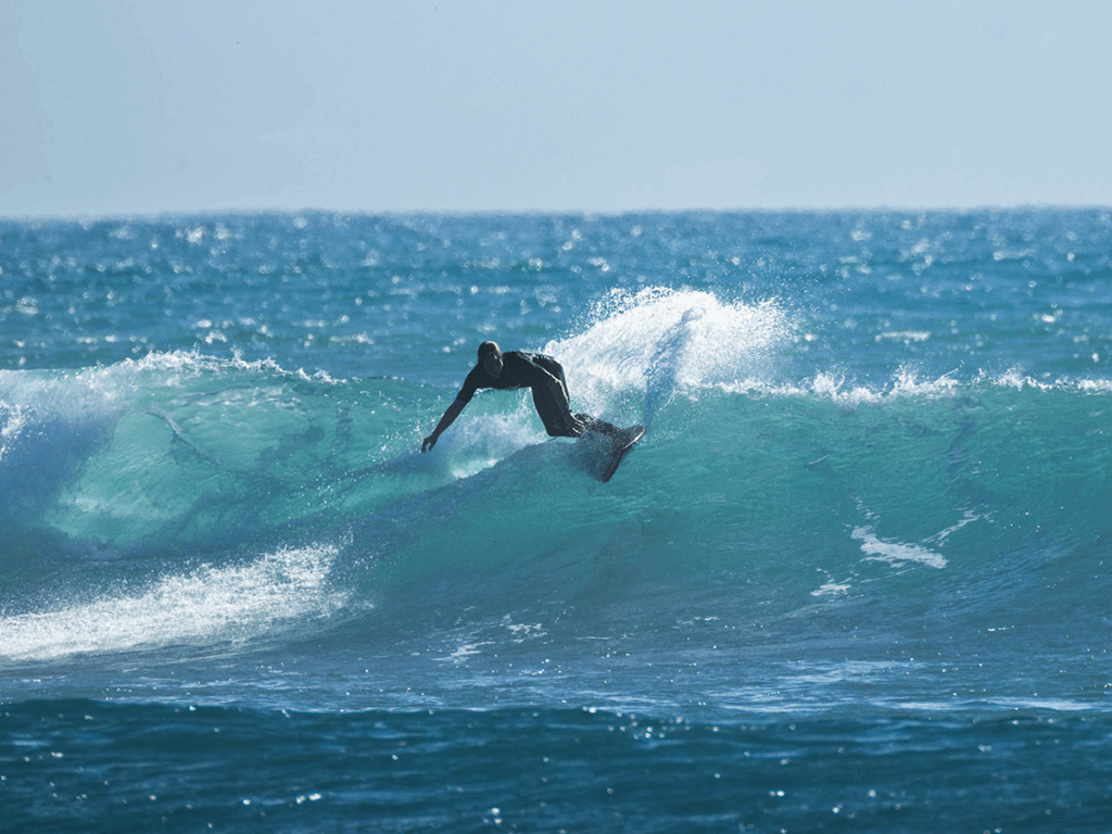 Jeremy surfs a wave at Raglan beach